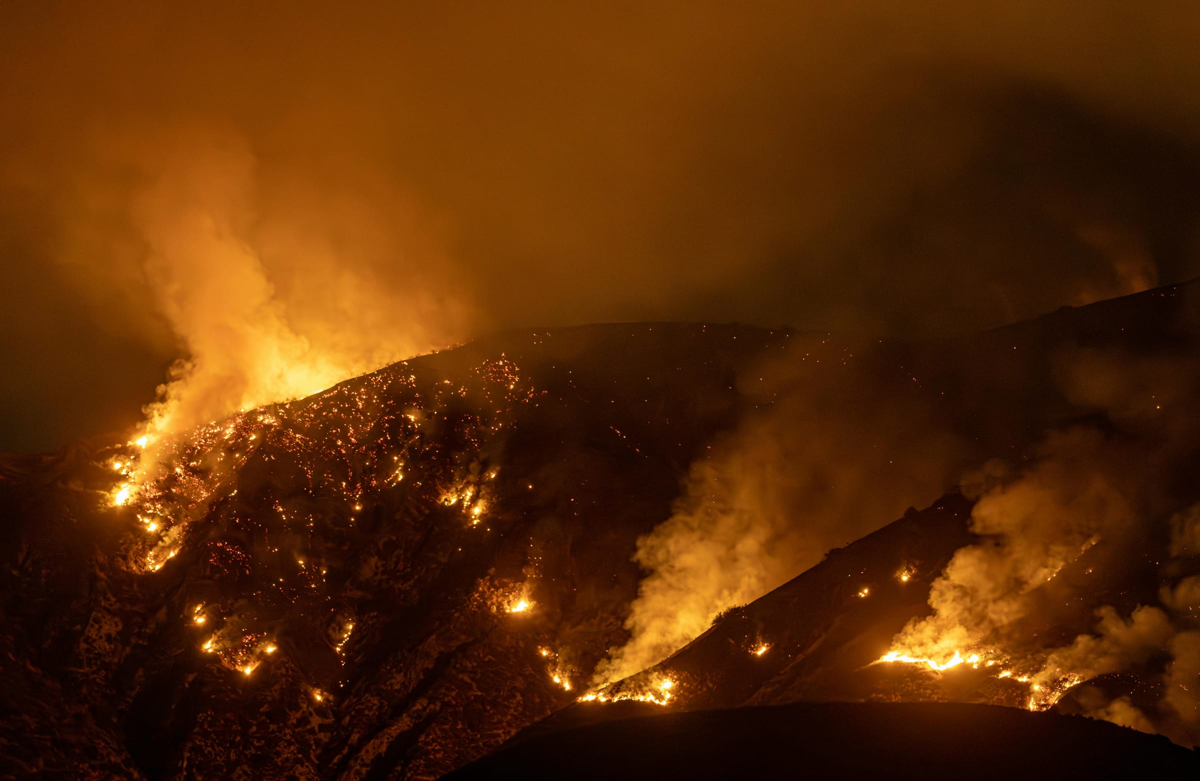 Wildfire burning across a dark hillside at night